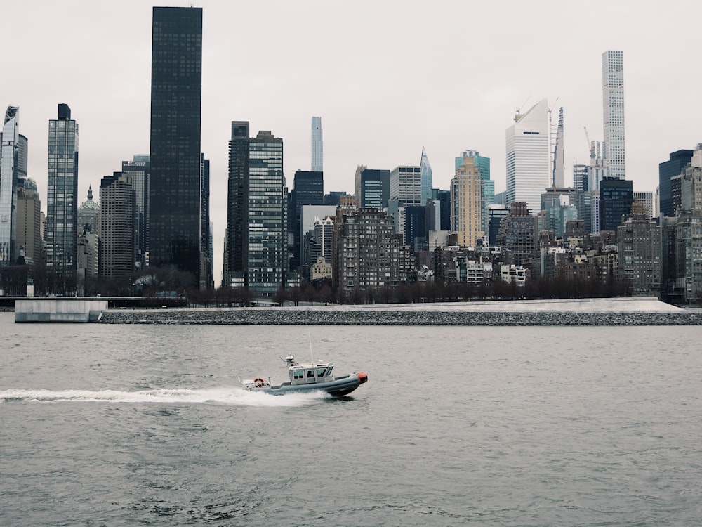 white and black boat on sea near city buildings during daytime