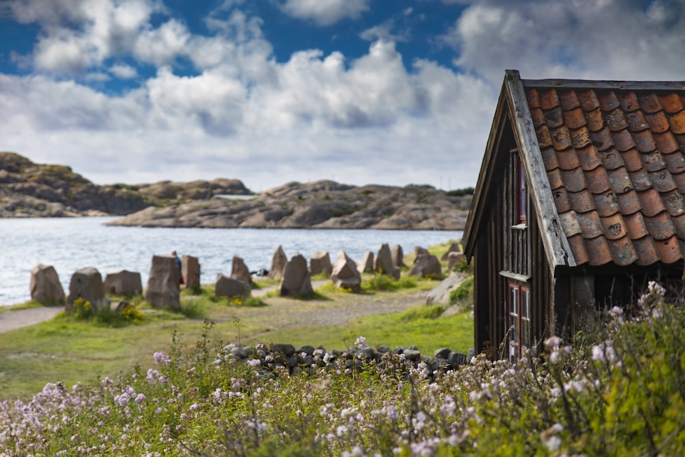 brown wooden house near body of water under blue sky during daytime