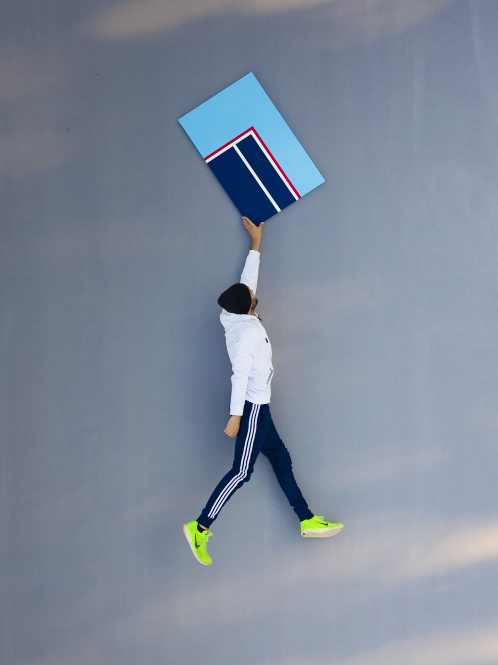 man in white shirt and white pants holding blue and white board