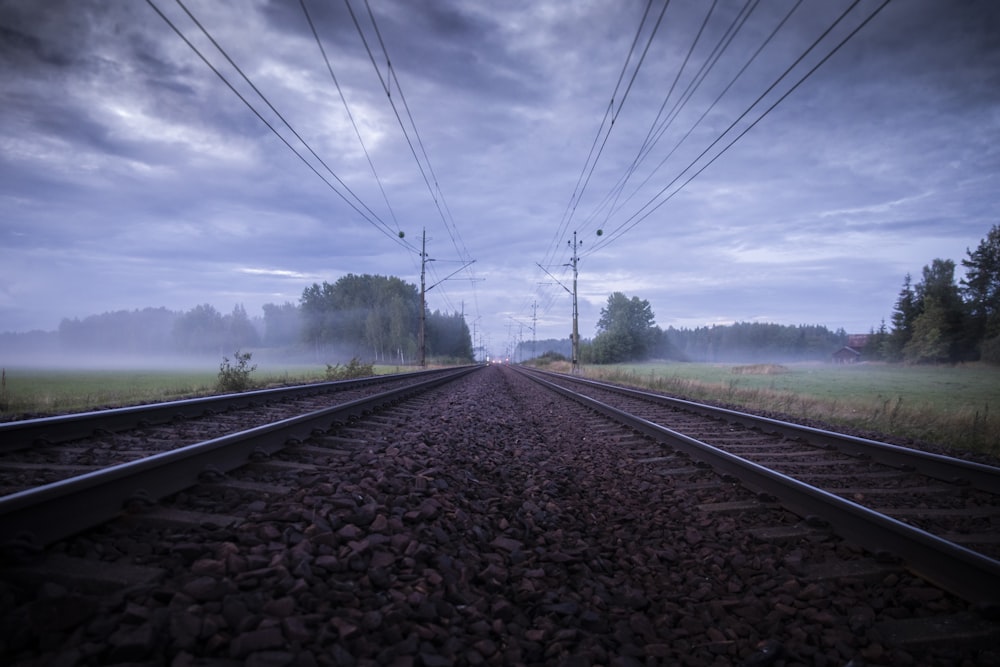 train rail road between green grass field during daytime