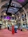 The interior of a large, ornately designed building with arched ceilings and intricate architectural details. The space features gaming machines lined up along the floor, under a high ceiling with a grid pattern. Lighting in purple and white tones enhances the ambiance.