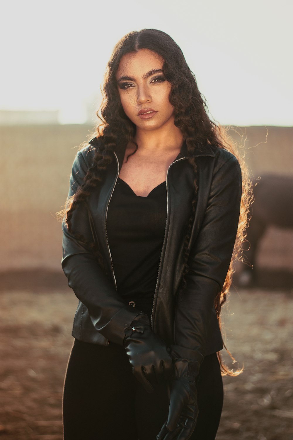 woman in black leather jacket standing on brown grass field during daytime