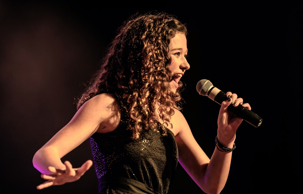 woman in black sleeveless dress singing