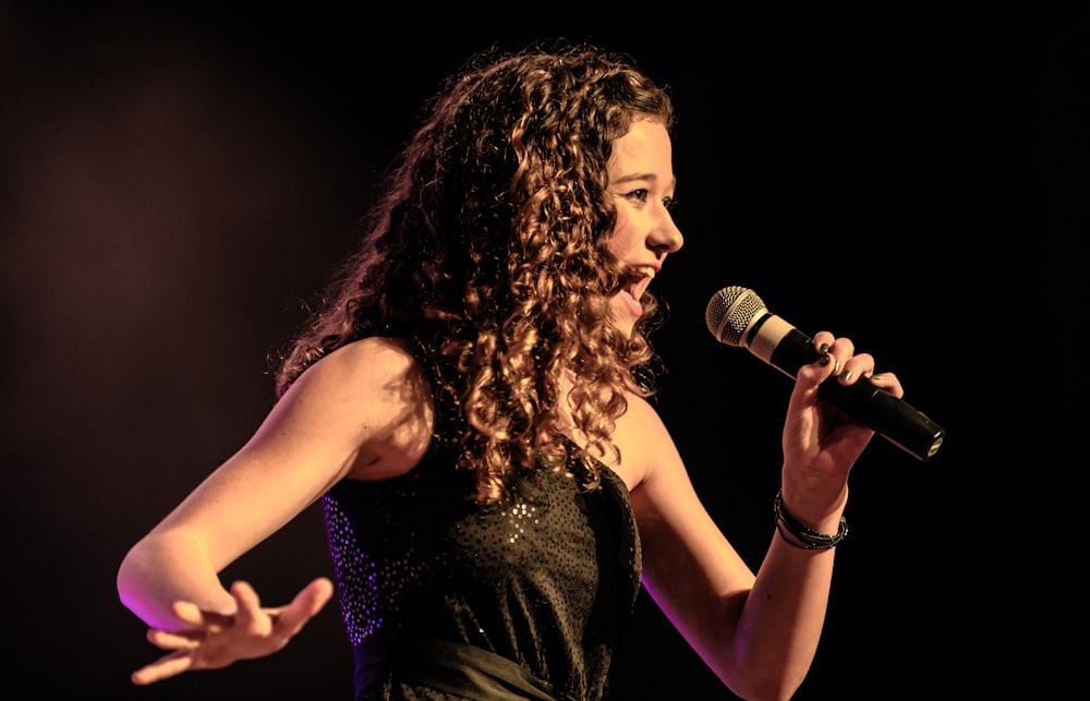 Mujer con vestido negro sin mangas cantando