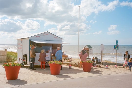 people sitting on bench near body of water during daytime in Cabourg France