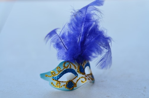 A delicate navy blue and champagne masquerade mask resting on elegant fabric.