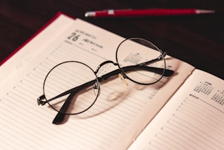 Calendar and planner with notes, pens, and eyeglasses on desk