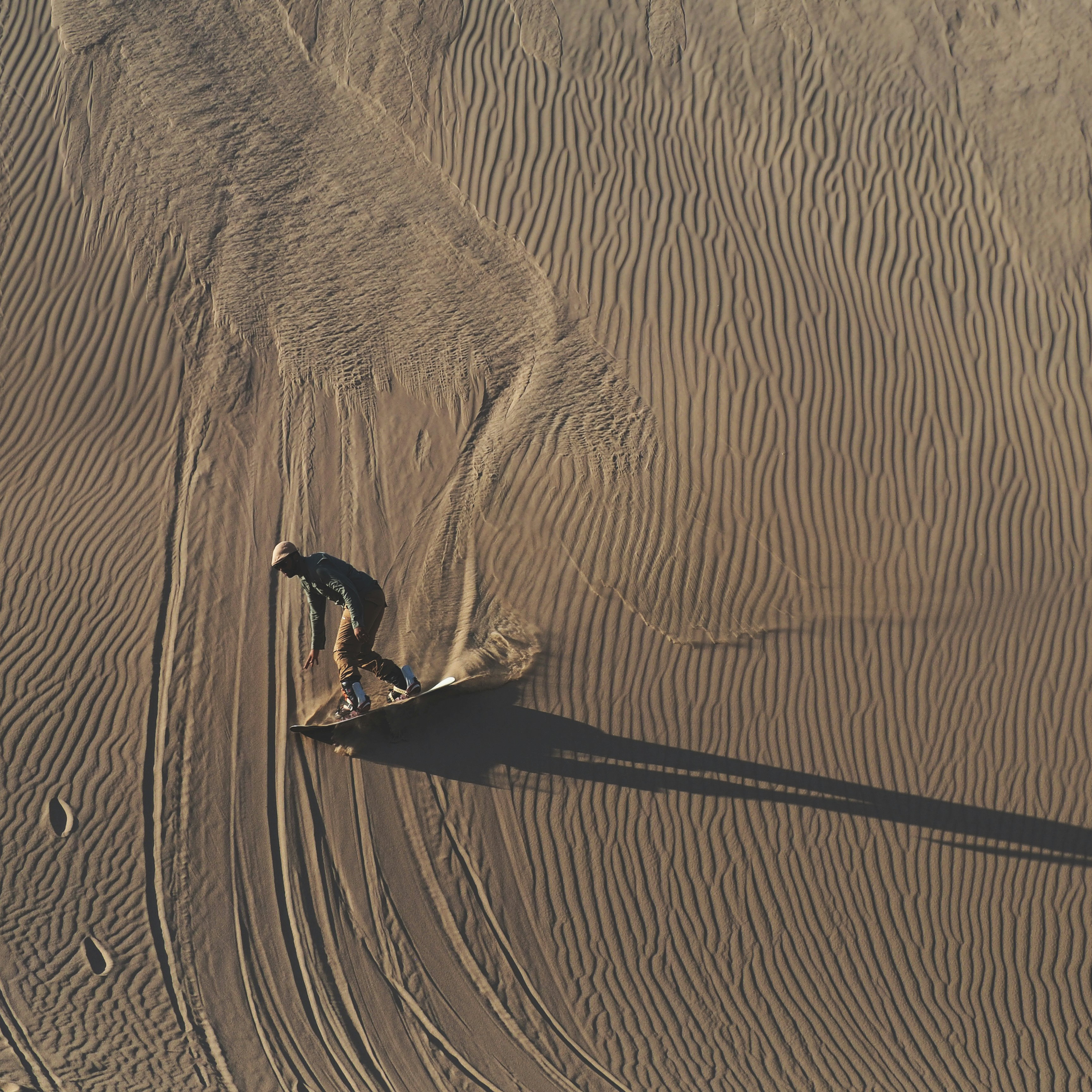 person in black shirt walking on brown sand