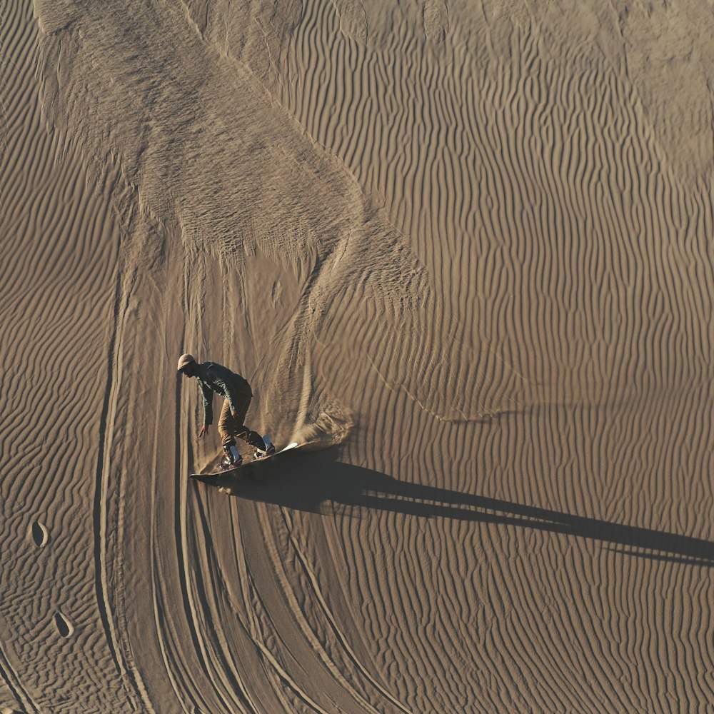 Persona in camicia nera che cammina sulla sabbia marrone