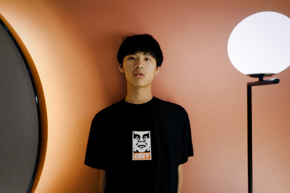 boy in black crew neck t-shirt standing near wall