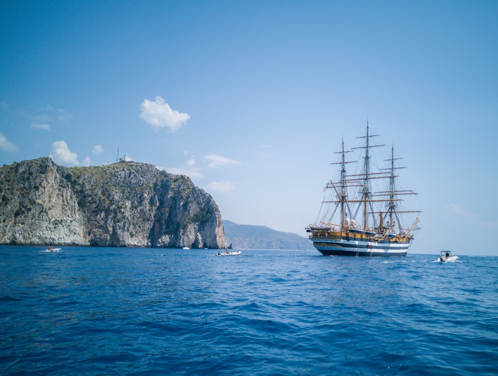 brown ship on sea near mountain under blue sky during daytime