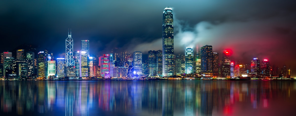Hong Kong skyline panoramic view across Victoria Harbour at night with city lights reflecting on the water