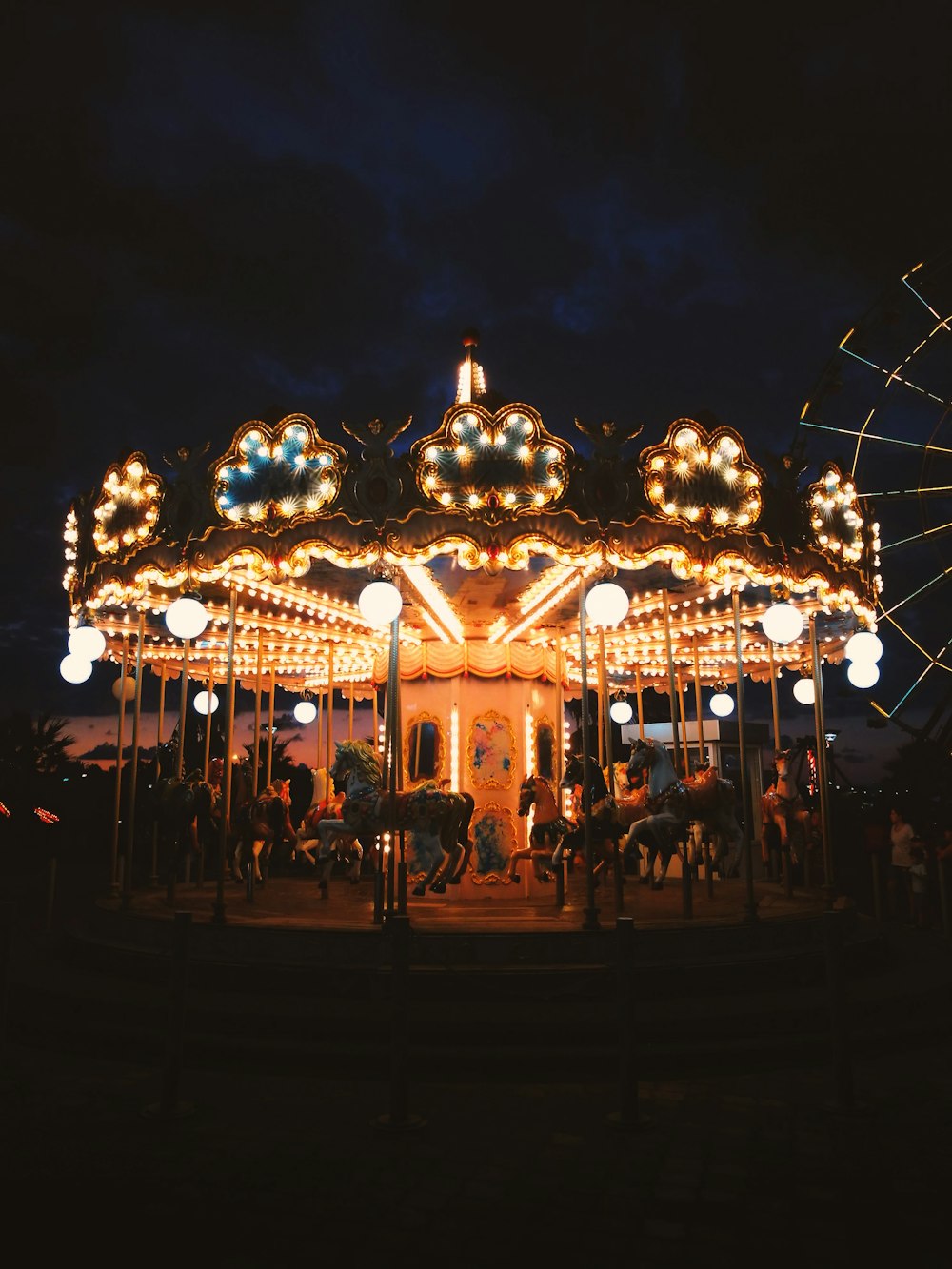 people standing near lighted carousel during night time