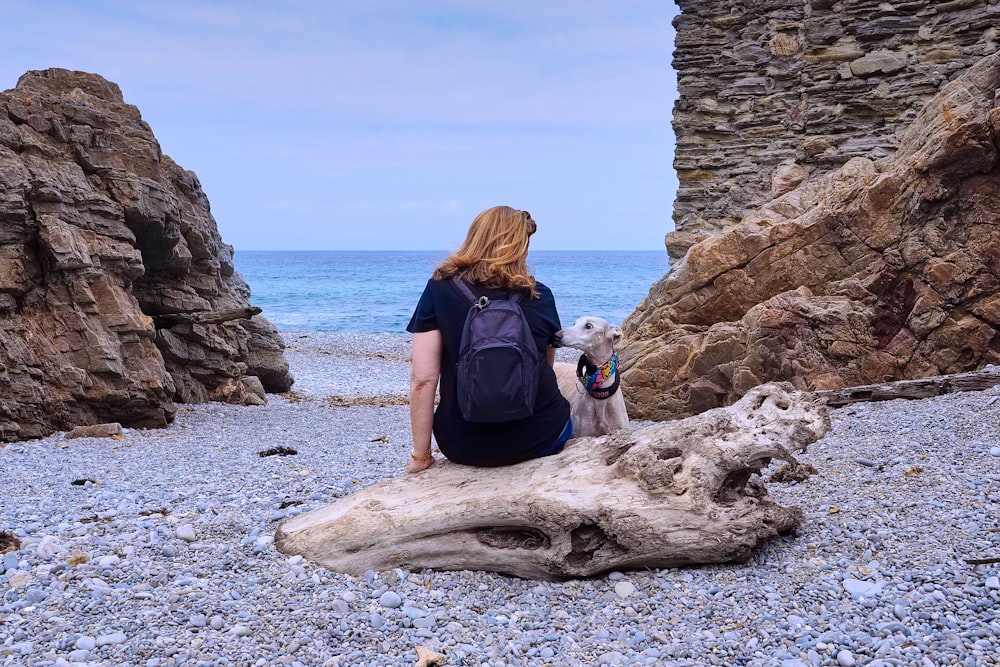 woman in black t-shirt sitting on brown rock formation near sea during daytime