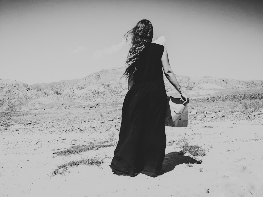 woman in black dress walking on sand