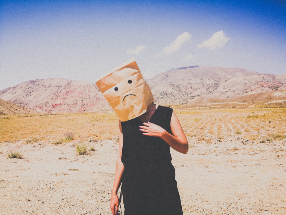 woman in black dress holding brown paper bag