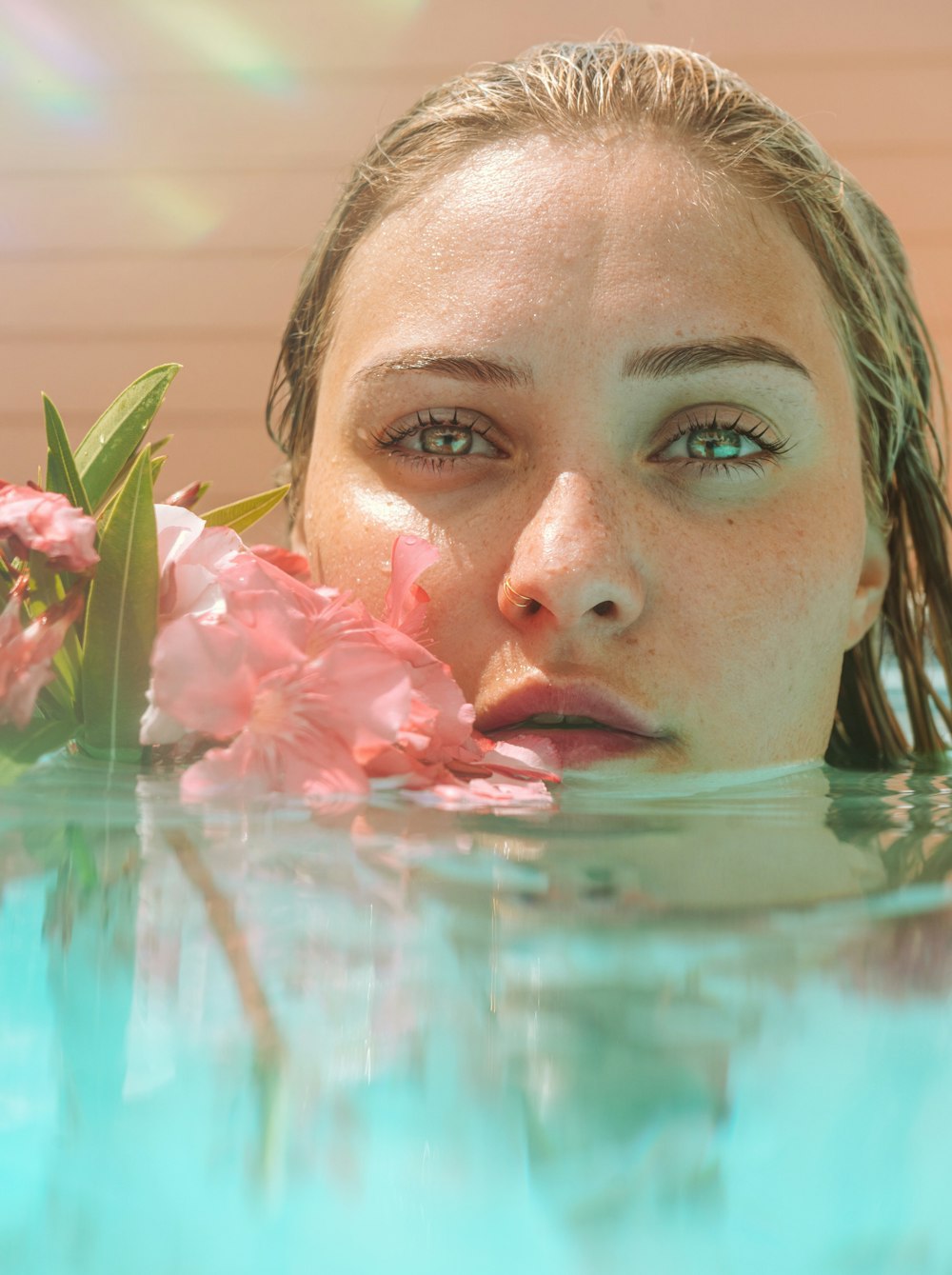 mujer en el agua con pétalos de flores rosas