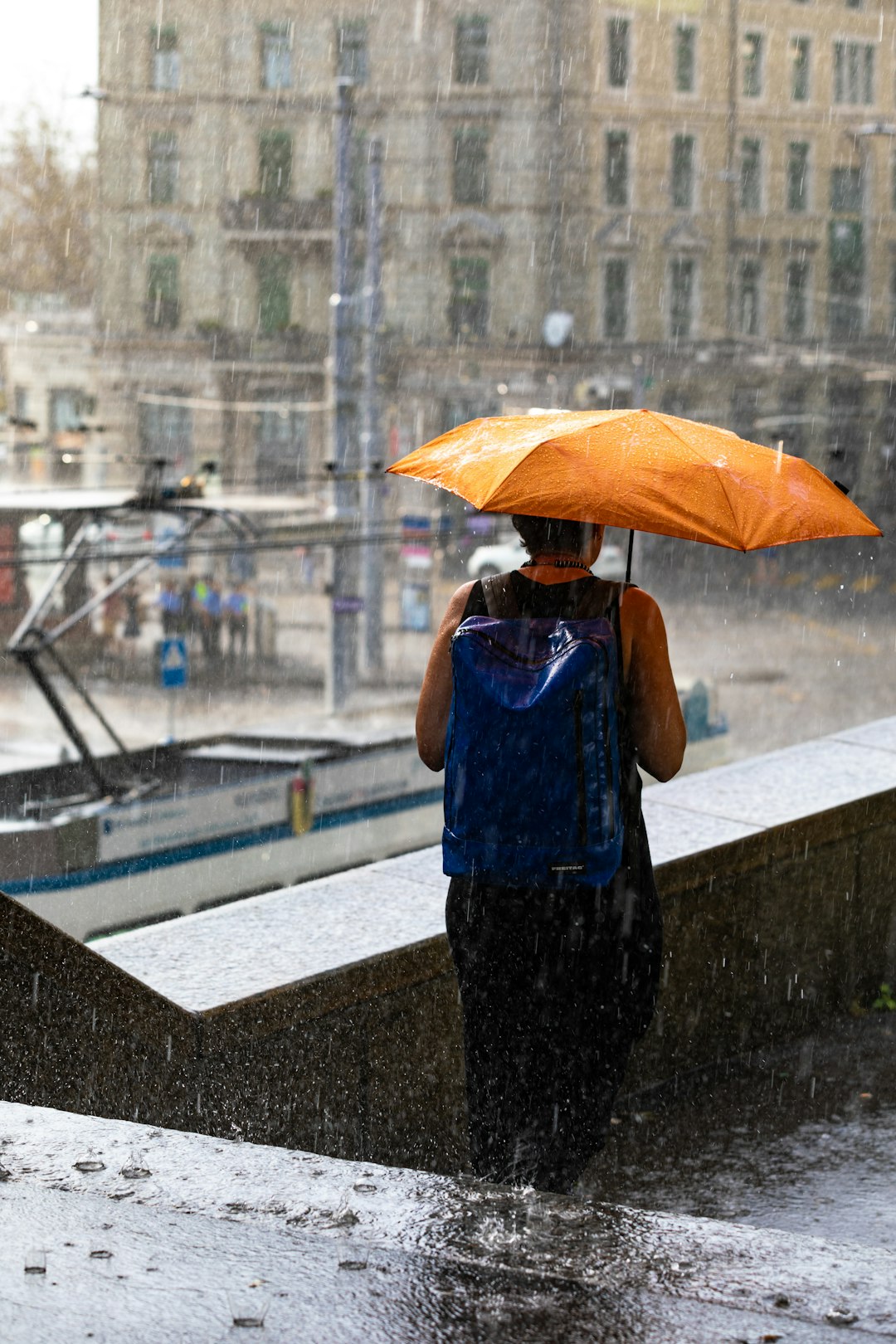 man in blue tank top and black shorts holding orange umbrella