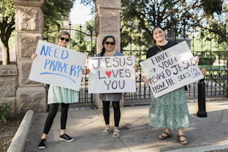 2 women holding white and blue happy birthday signage