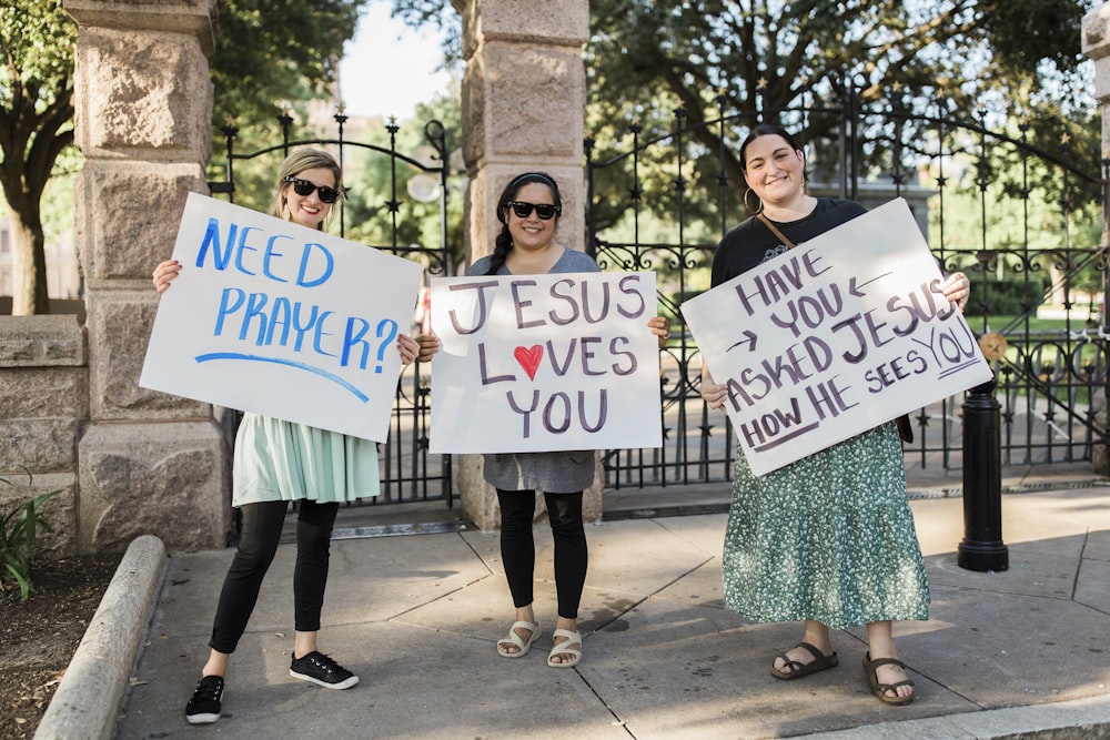 2 women holding white and blue happy birthday signage