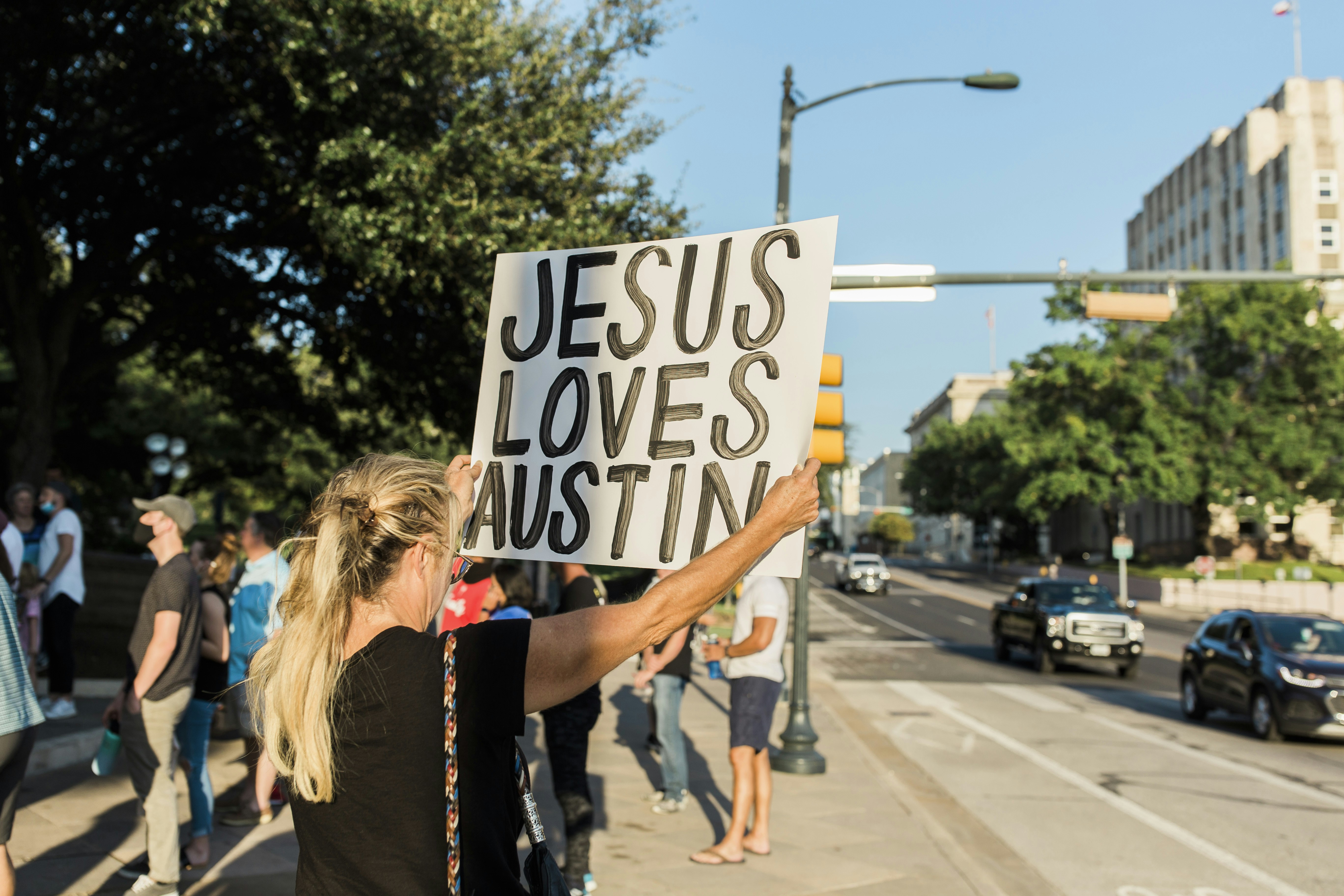 Donna in camicia nera che tiene il segnale di divieto di parcheggio bianco e nero