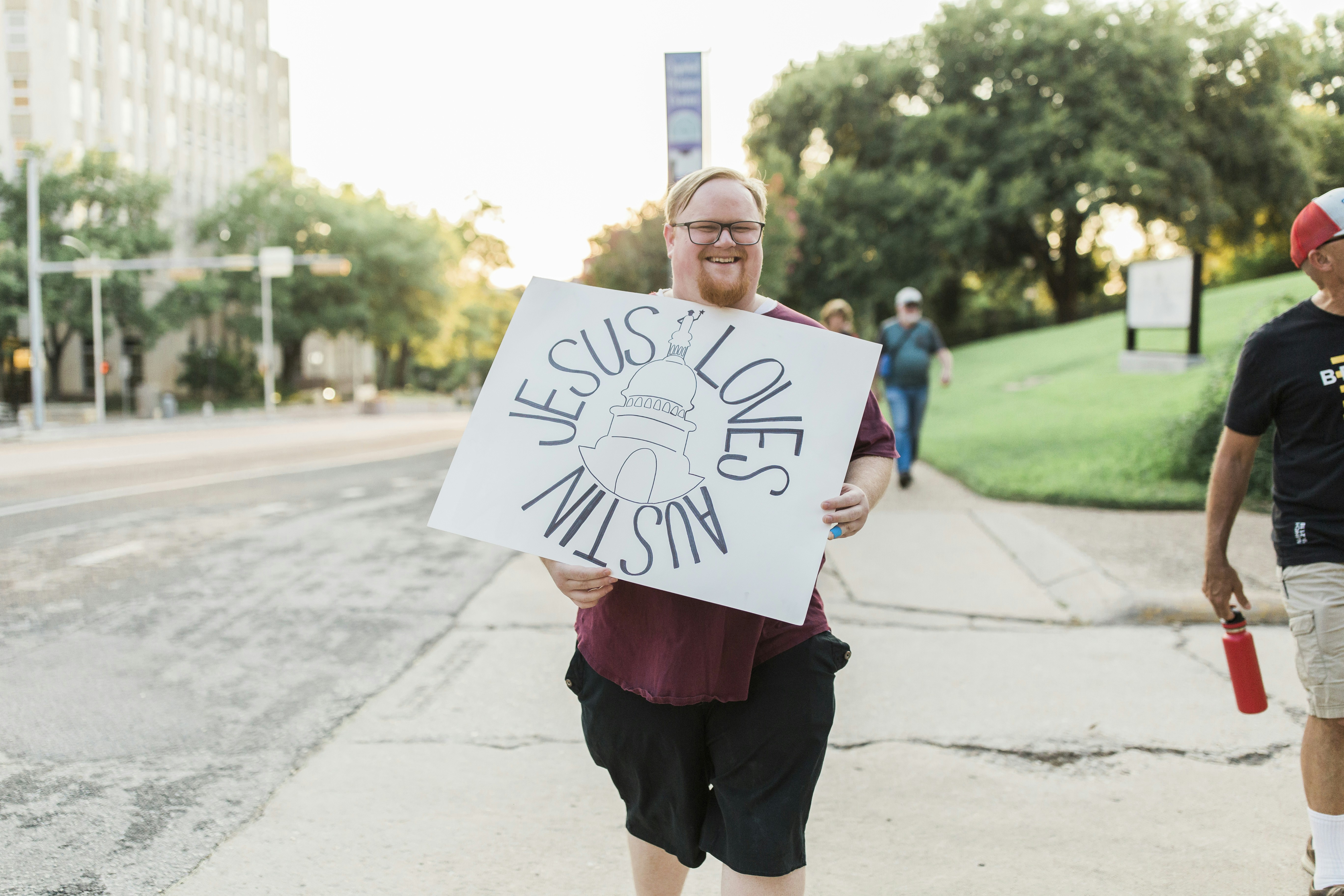 man in red crew neck t-shirt holding white printer paper