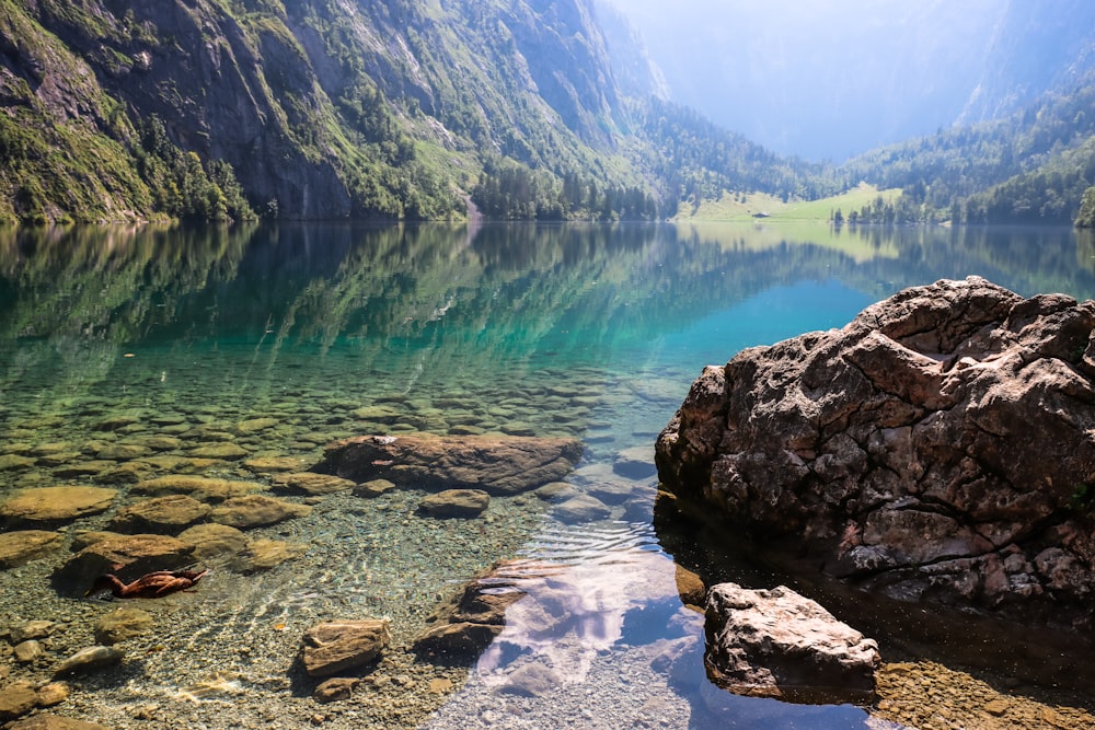 green lake surrounded by mountains during daytime