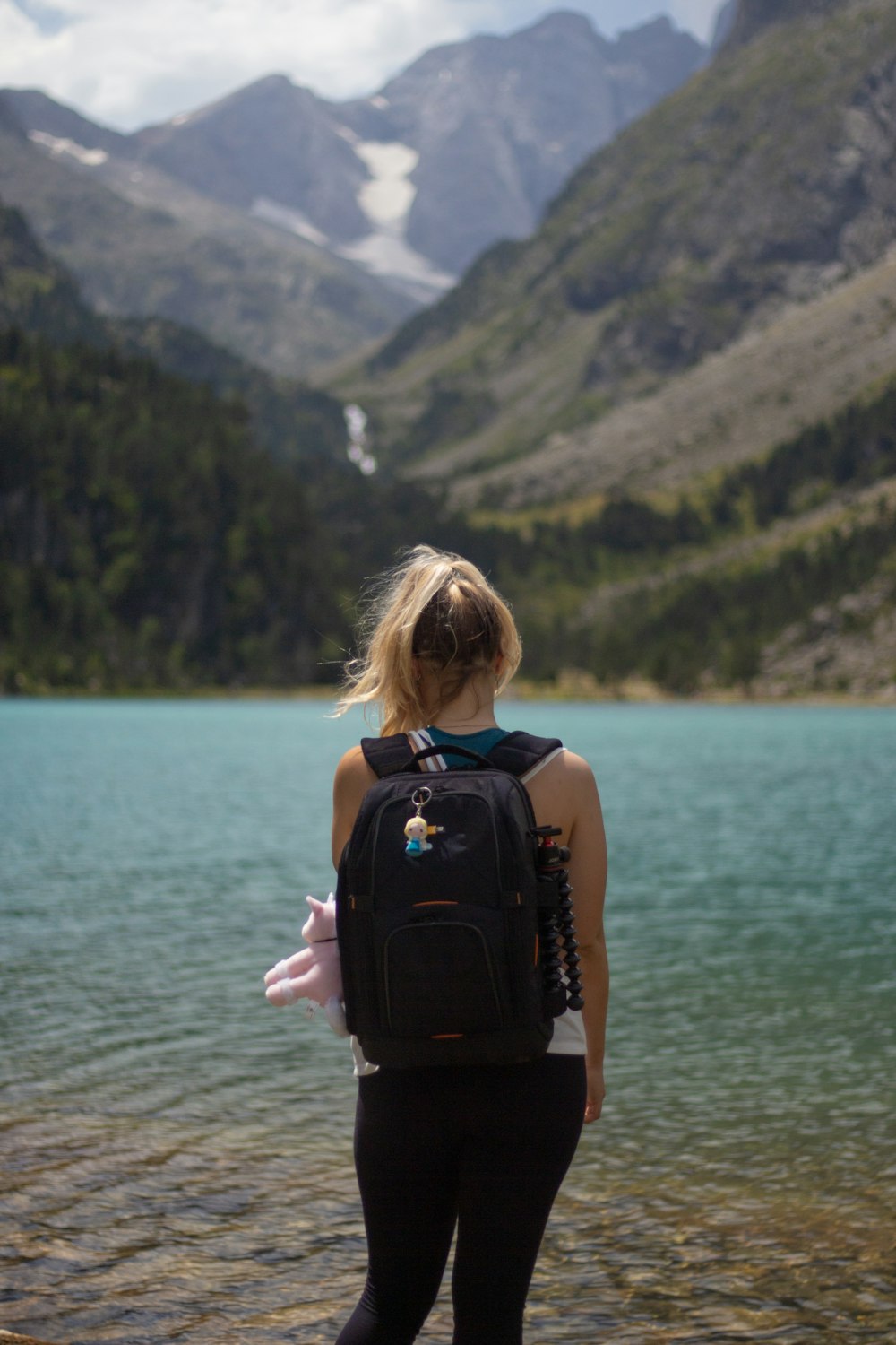 woman in black tank top carrying black backpack standing on seashore during daytime