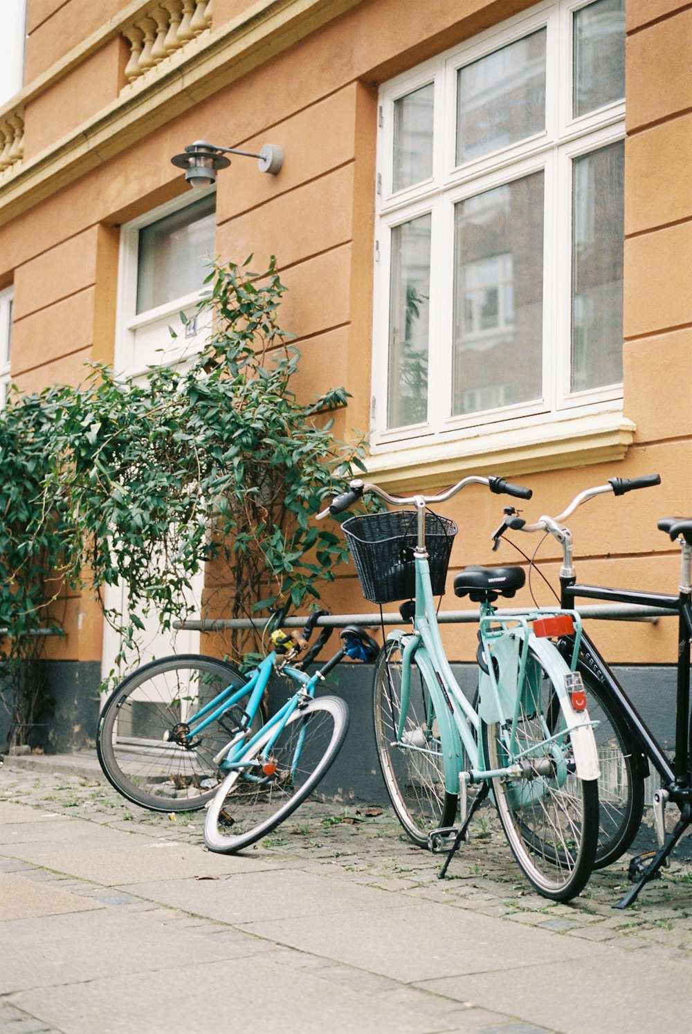 blue city bike parked beside brown concrete building during daytime