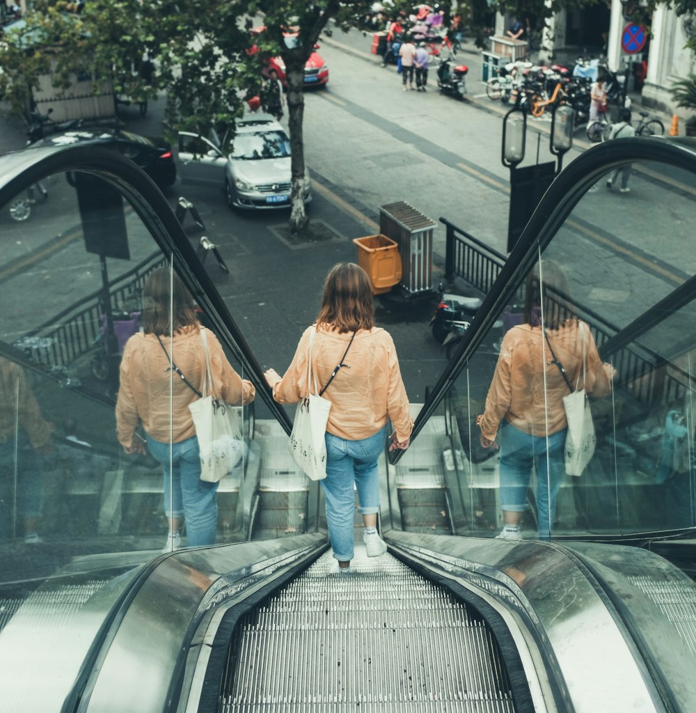 woman in brown jacket and blue denim jeans walking on the street