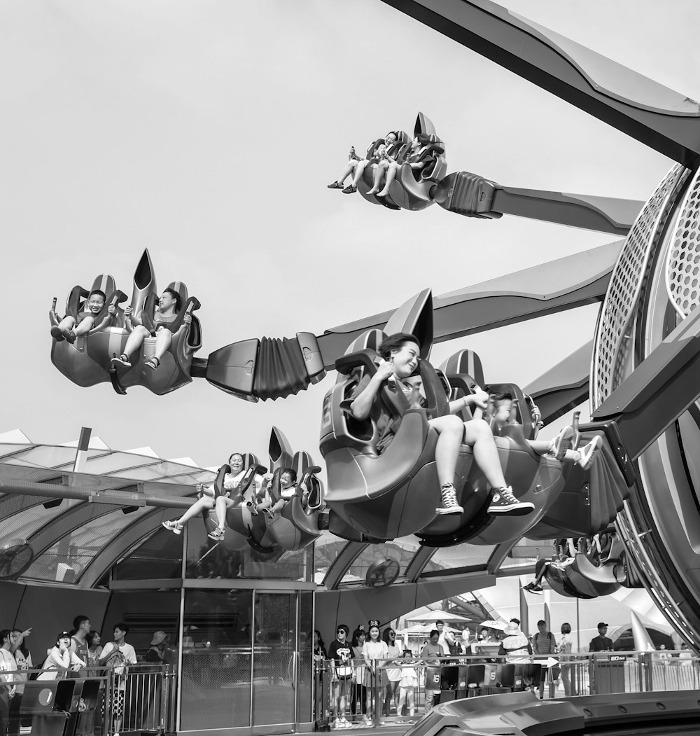 grayscale photo of people riding on a roller coaster
