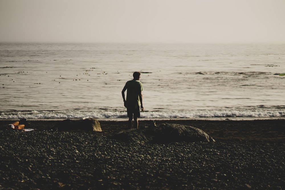 a man standing on top of a beach next to the ocean