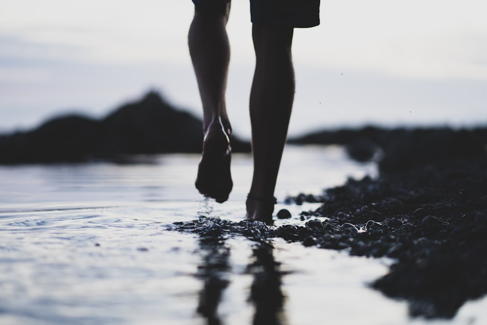 person in black shorts standing on water during daytime