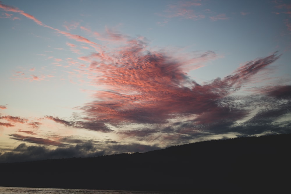 a pink cloud in the sky over a body of water