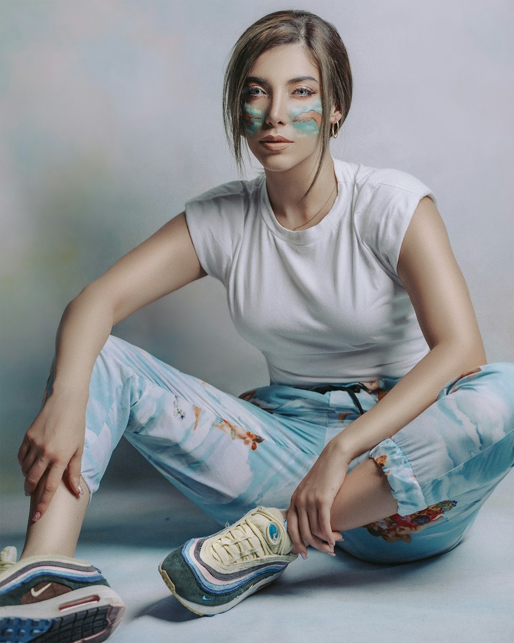 woman in white crew neck t-shirt and blue and white pants sitting on floor