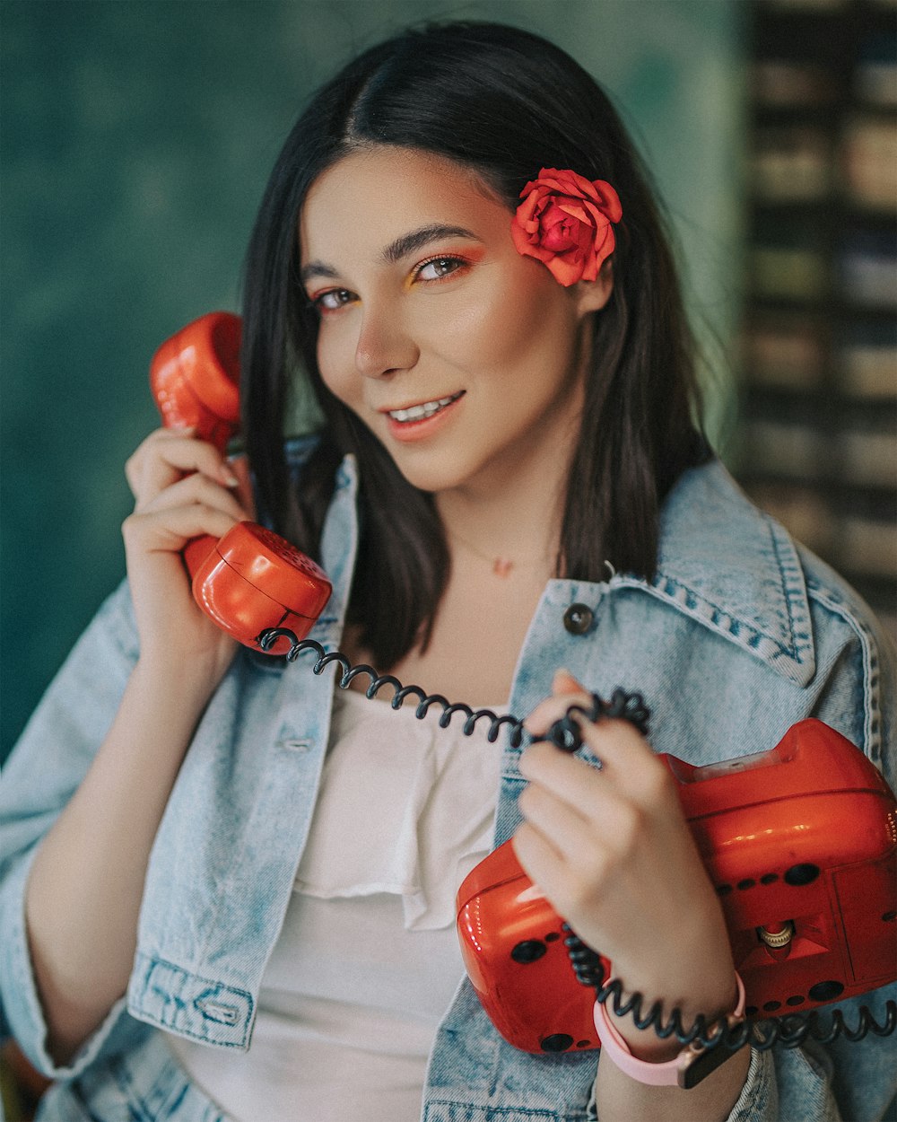 woman in blue denim jacket holding red telephone