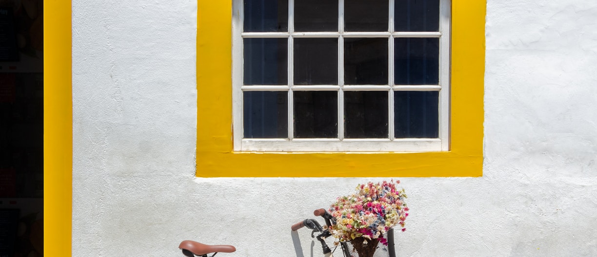 blue city bike parked beside yellow painted wall