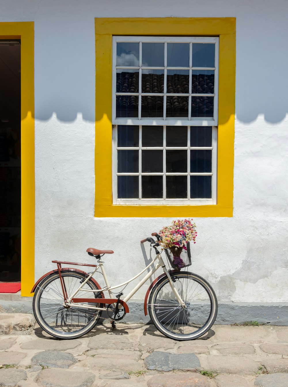 blue city bike parked beside yellow painted wall