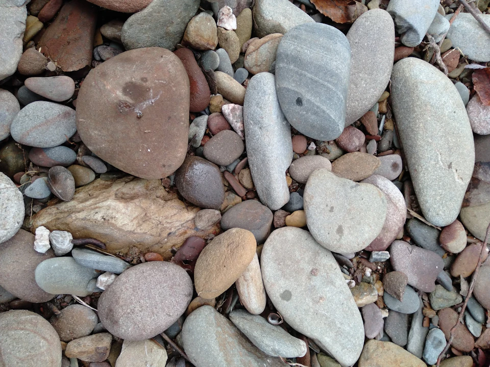 Close-up view of a rocky beach scene with diverse types of rocks scattered across sandy