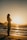 silhouette of woman standing on seashore during sunset
