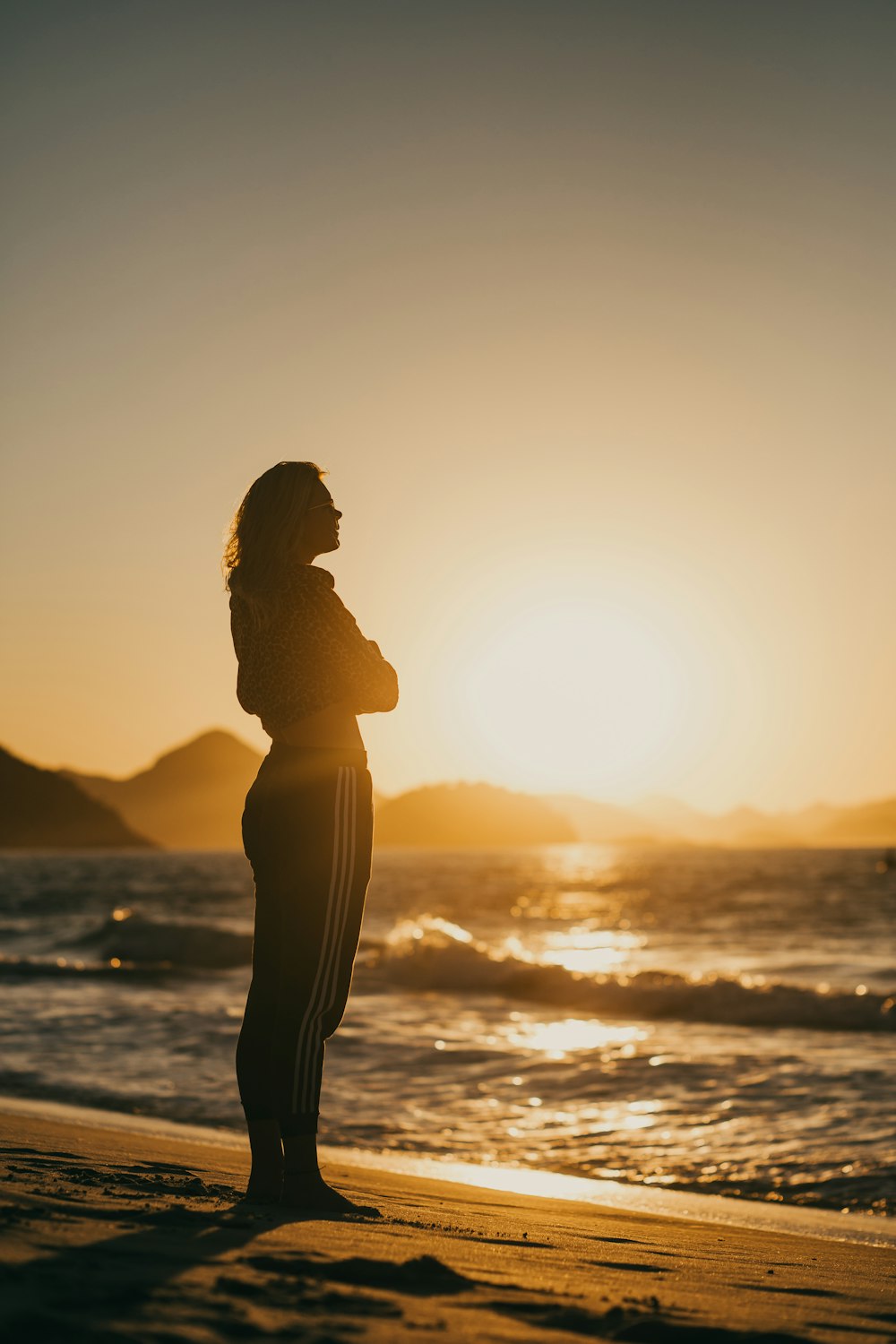 Foto silueta de mujer de pie en la orilla del mar durante la puesta de sol  – Imagen Puesta de sol gratis en Unsplash