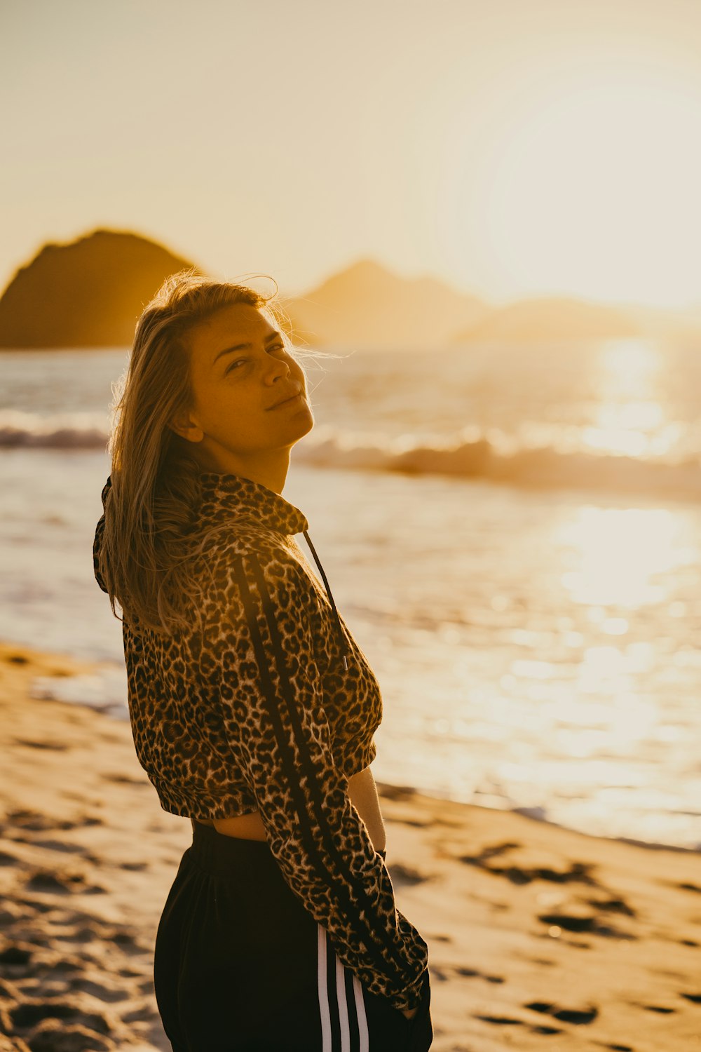 woman in black and white dress standing on beach during sunset