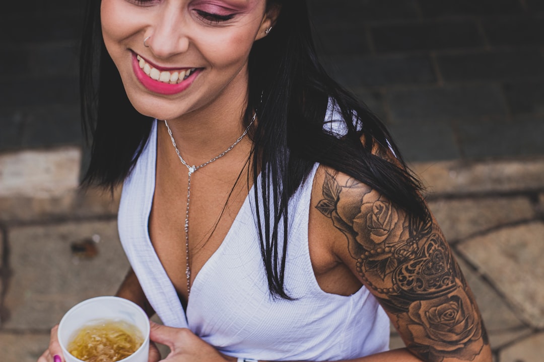 woman in white tank top holding white ceramic mug