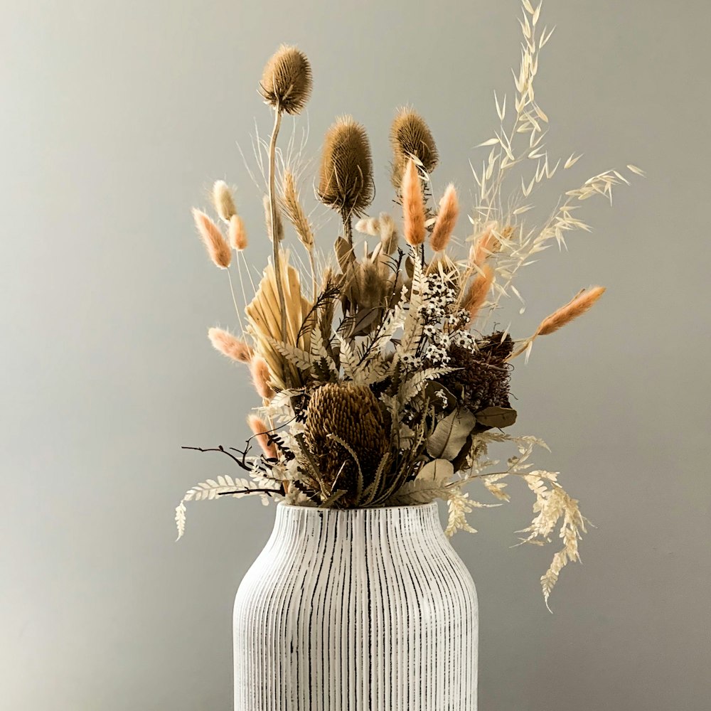 white and brown flowers in white ceramic vase