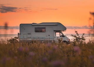 white and gray rv on green grass field during sunset