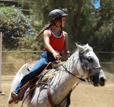 woman in blue long sleeve shirt riding white horse during daytime