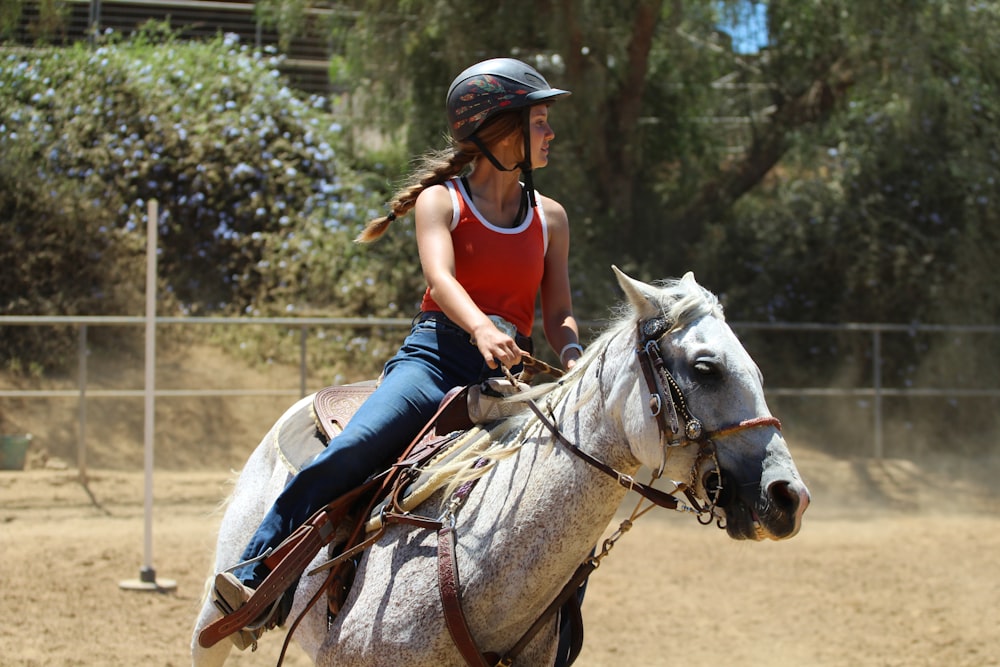 woman in blue long sleeve shirt riding white horse during daytime