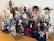 A collection of diverse, cultural figurines arranged on a wooden surface. The dolls are dressed in traditional attire from various cultures, including elaborate dresses, headpieces, and accessories. Materials vary, with some made of ceramic, fabric, or wood, showcasing intricate details and craftsmanship.