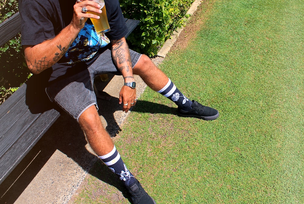 man in black and white nike shoes sitting on green grass field during daytime