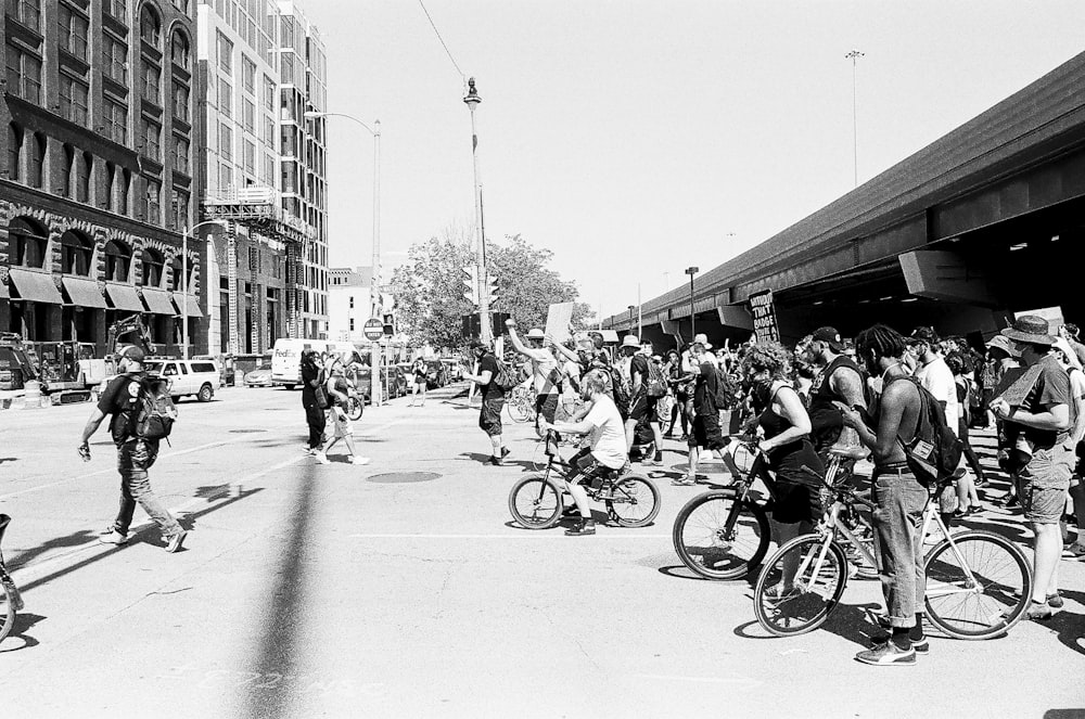 people riding bicycles on street in grayscale photography